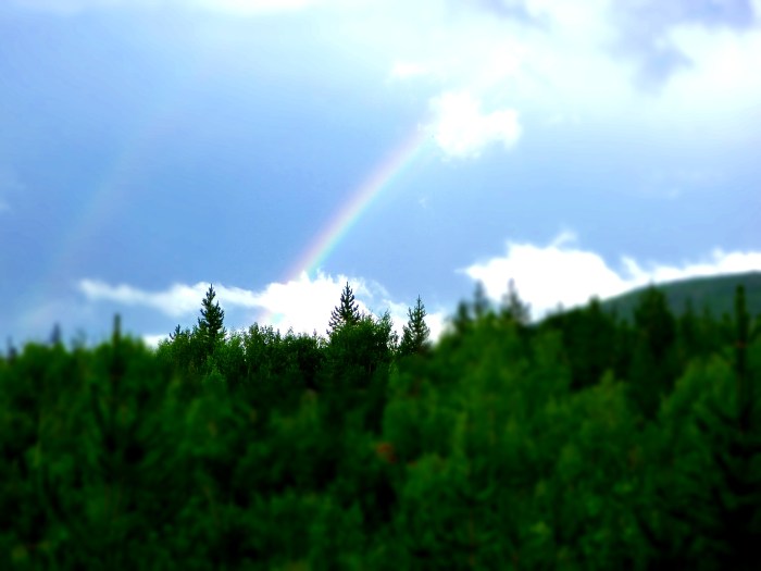 A rainbow is seen in the distance after a late afternoon storm while hiking on backpacking trip.